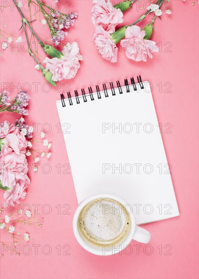 Overhead view coffee cup blank notepad with carnations gypsophila