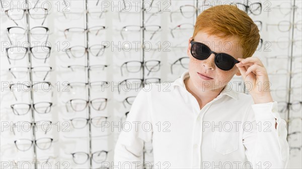 Freckle boy with black eyeglasses posing optics shop