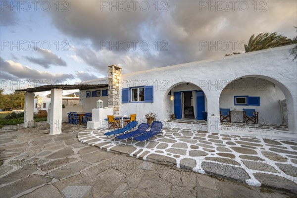 White Cycladic house with terrace with chairs and sun loungers