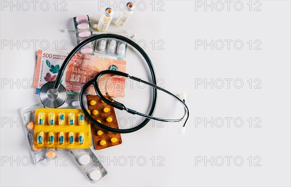 High angle view of stethoscope with pills on money isolated. Stethoscope with medicaments on Nicaraguan Cordobas. High cost of medical health with stethoscope