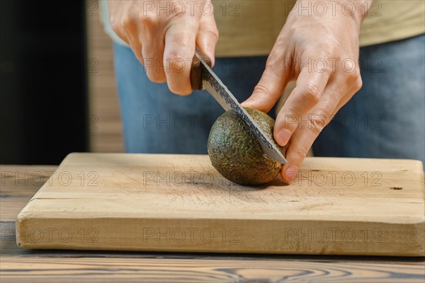 Unrecognizable man cuts avocado on half