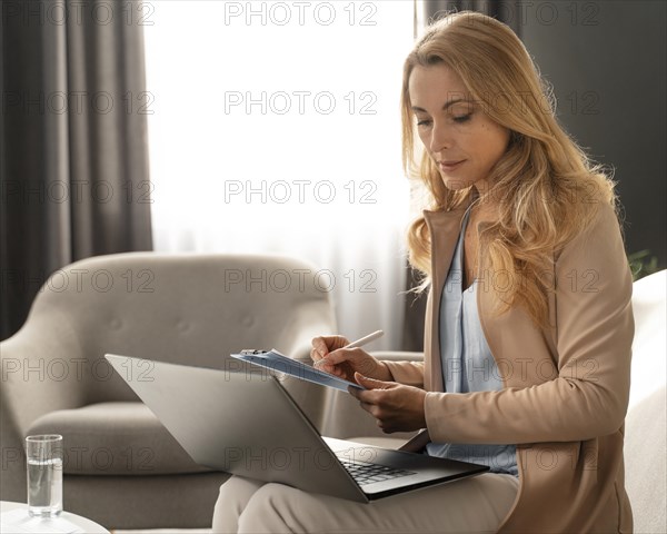 Mid shot woman therapist taking notes with laptop lap