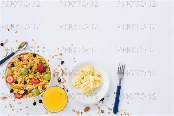 Scrambled eggs juice glass cornflakes with dried fruits white background