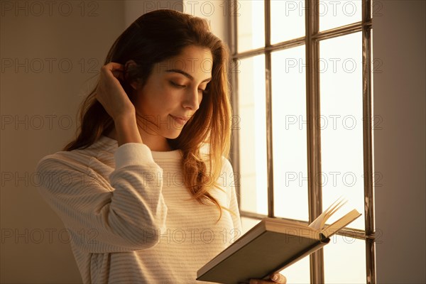 Side view young woman reading book home