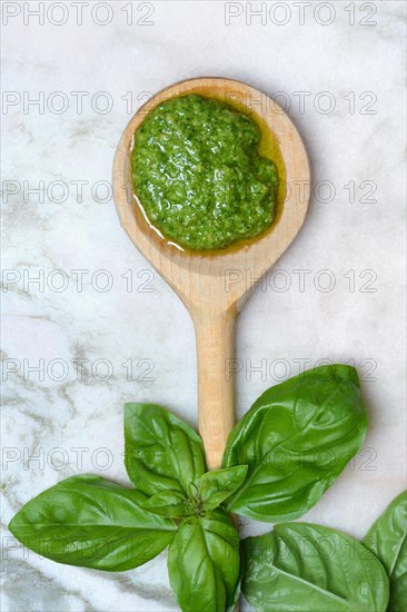 Pesto in wooden spoon and basil