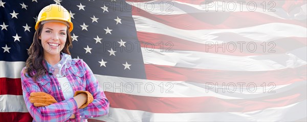 Female contractor wearing blank yellow hardhat and gloves over waving american flag background banner