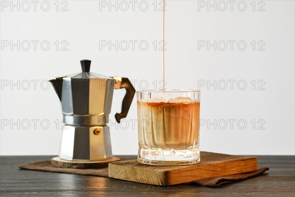 Pouring cream into coffee with ice