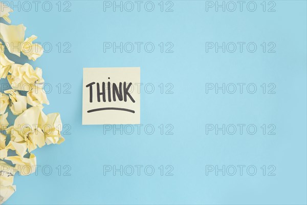 Crumpled yellow paper with think witten text adhesive note blue background