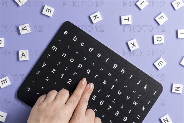 Fingers touching braille alphabet board