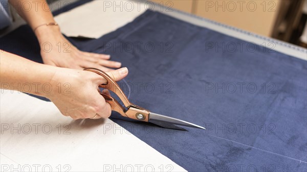 Hands cutting material with scissors close up