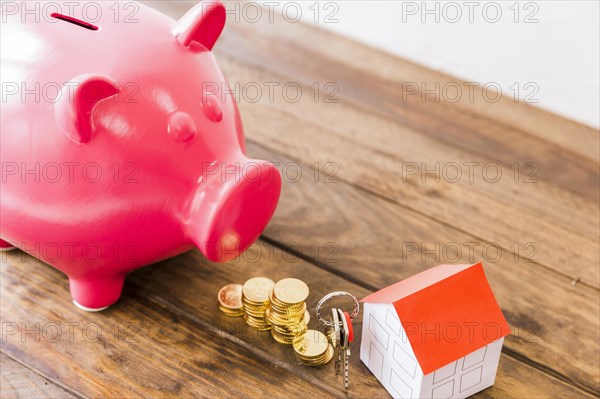 Piggybank stacked coins house key wooden desk