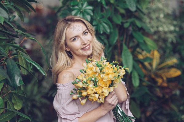 Portrait blonde young woman holding yellow flower bouquet