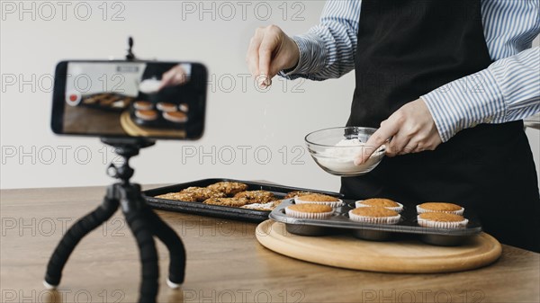 Female food blogger streaming home with smartphone while cooking