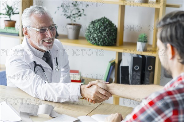 Cheerful doctor shaking hand patient