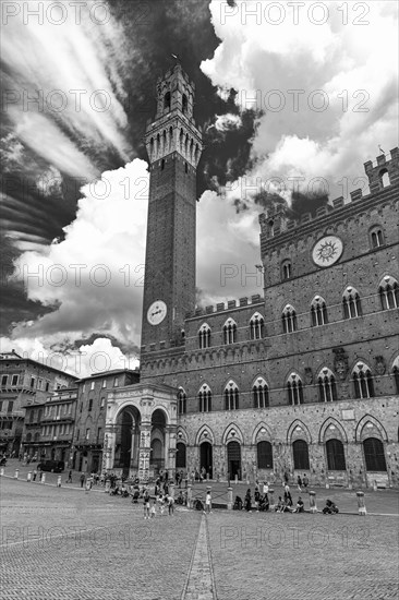 Atmospheric clouds at Piazza del Campo with its bell tower Torre del Mangia and the town hall Palazzo Pubblico