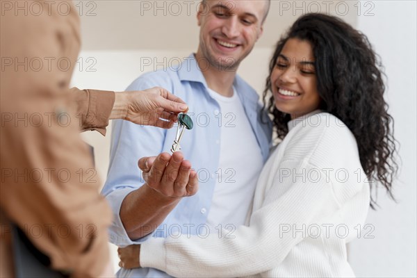 Happy couple receiving keys their new home from realtor