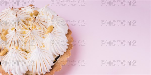 Close up lemon tart with italian meringue pink backdrop