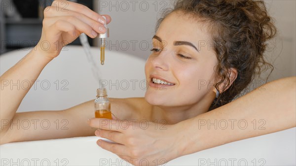 Woman relaxing bathtub with serum