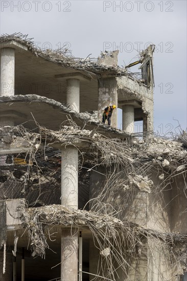 Ruin of a concrete building with many rebar wires and a worker