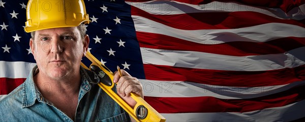 Male contractor wearing blank yellow hardhat over waving american flag background banner