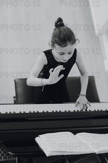 Elegant girl sits at the concert grand and plays the piano