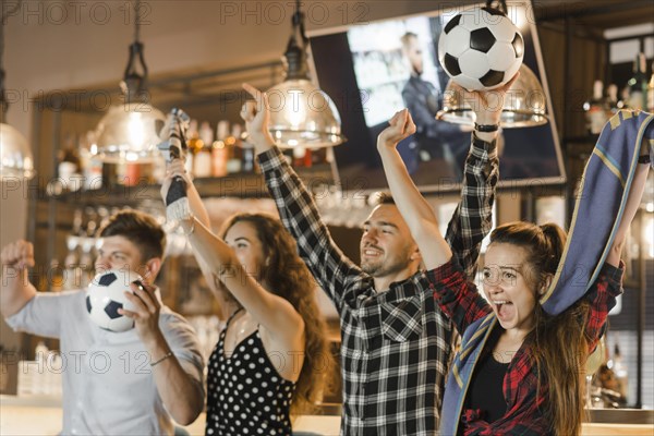 Group friends watching sport together celebrating victory bar