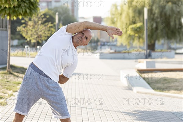 Elder man stretching sidewalk