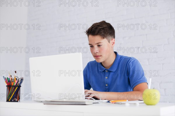 Serious guy studying with laptop desk