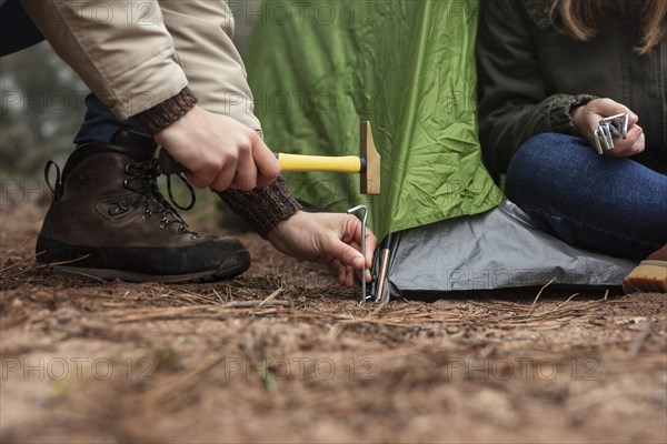 Close up people putting up green tent