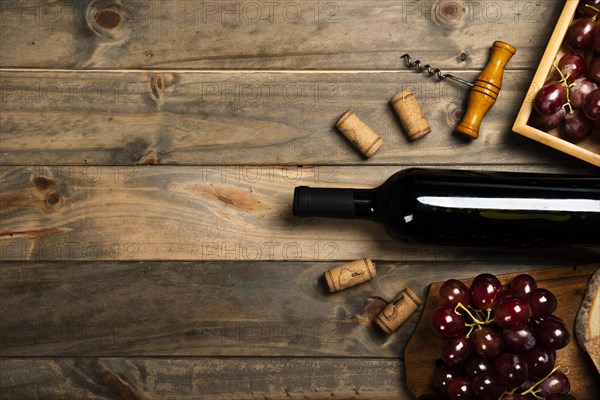 Flat lay bottle wine surrounded by corks red grapes