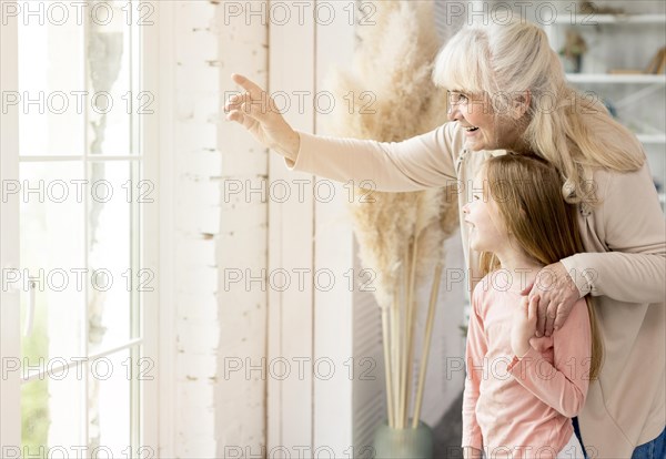 Grandma with girl home looking window
