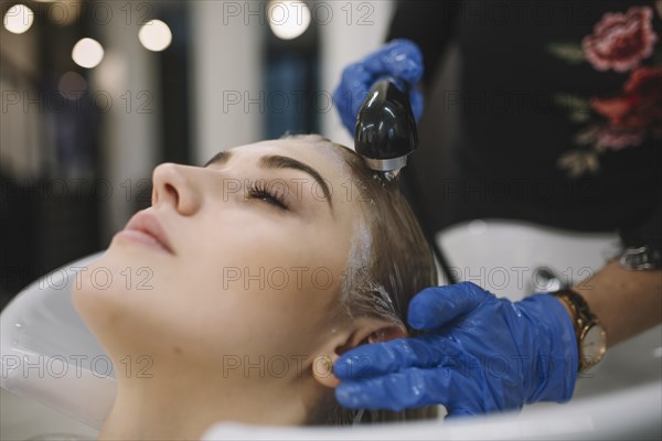 Hairdresser washing head client after dyeing