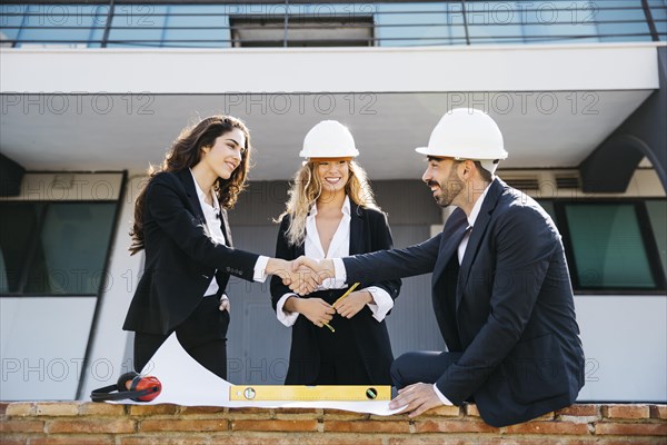 Architects wearing helmets shaking hands