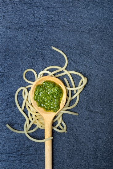 Pesto in cooking spoon and spaghetti