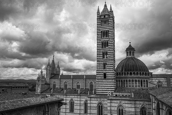 Dark clouds over the cathedral of Siena with its black and white striped marble facade