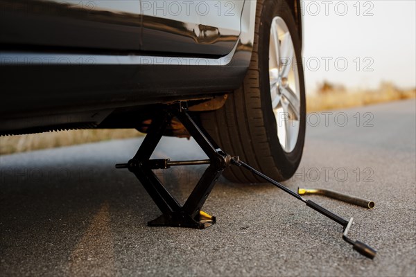 Black car lifted up by jack screw