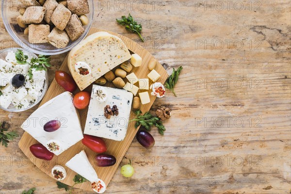 Cheese blocks with tomatoes parsley grapes wooden table