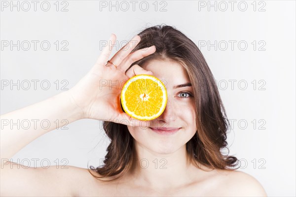 Smiling woman holding orange slice face