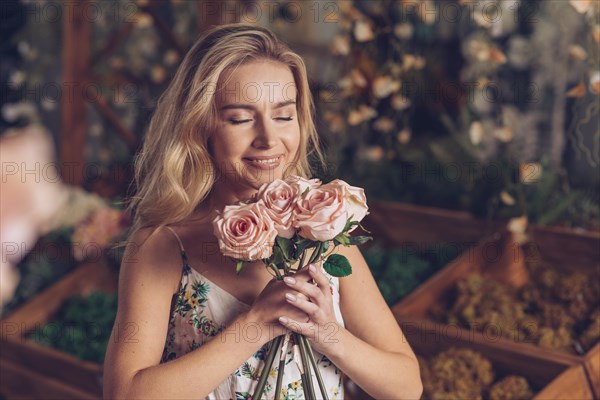 Close up young woman smelling pink roses