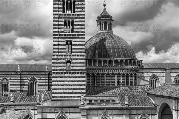 Dark clouds over the cathedral of Siena with its black and white striped marble facade