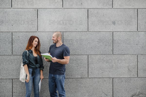 Man woman standing against gray wall