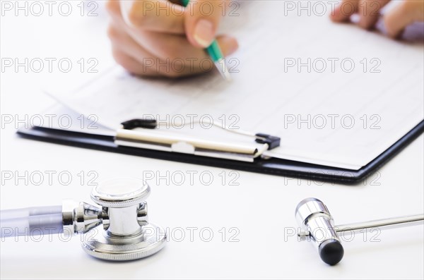 Close up doctor s hand holding pen checking medical report clipboard