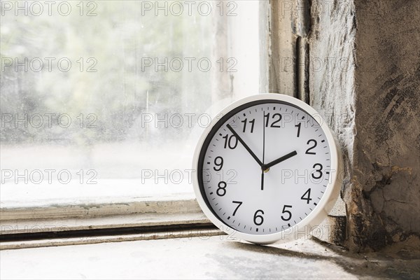 Close up small white round clock near glass window
