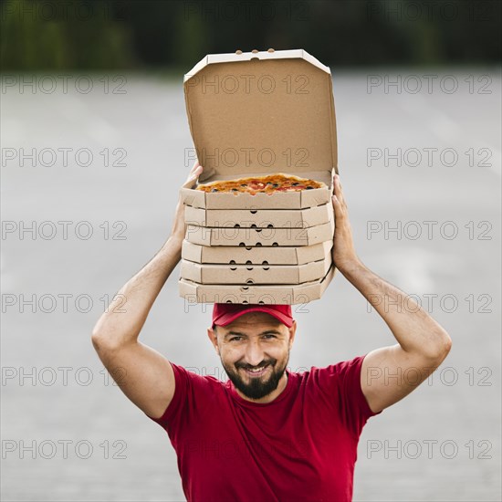 Front view delivery guy with pizza boxes his head