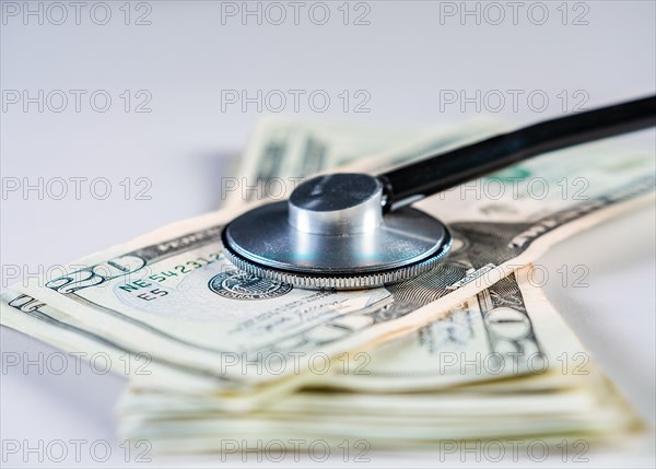 Close up of medical stethoscope on dollar bills isolated. Medical health cost concept