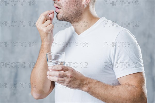 Young man holding glass water taking medicine