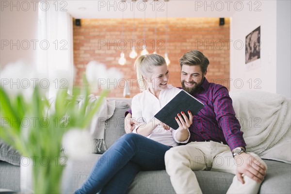 Cheerful young couple browsing tablet