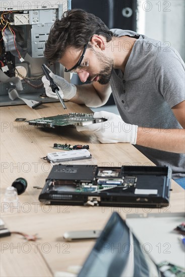 Male technician repairing computer motherboard wooden desk
