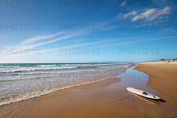 Sandy Atlantic ocean beach with surfboard at Fonte da Telha beach