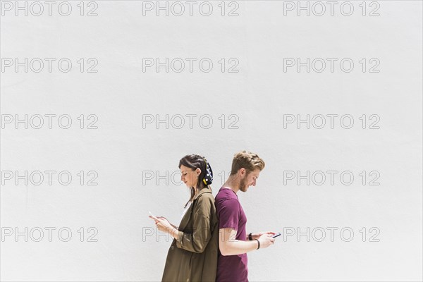 Young couple standing back back using cellphone